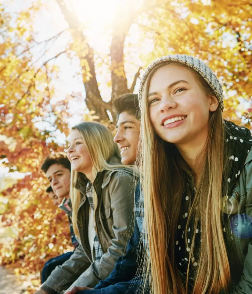 Jugendlichen sitzen in der Herbstsonne im Laubwald